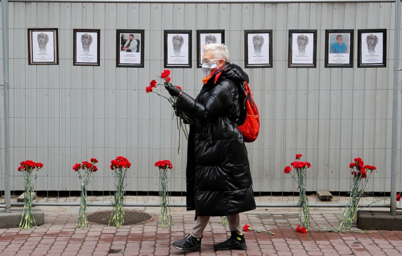 &copy; Reuters. Mulher segura flores com máscara de proteção perto de memorial improvisado para médicos que supostamente morreram de Covid-19 em São Petersburgo