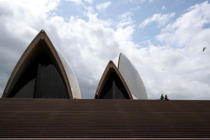 &copy; Reuters. FILE PHOTO: Tourists sit on the mostly deserted steps of the Sydney Opera House