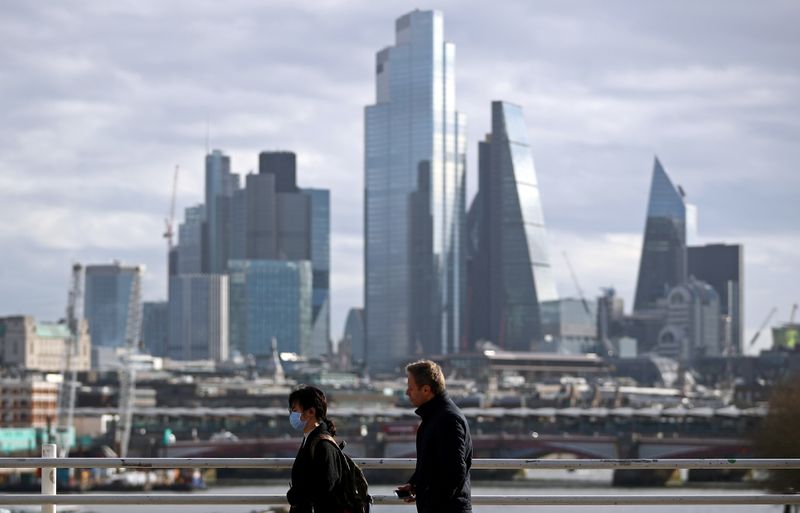 &copy; Reuters. FILE PHOTO: A woman wearing a protective mask walks across Waterloo Bridge in front of the City of London financial district during rush hour, as the number of Coronavirus cases grow around the world, in London