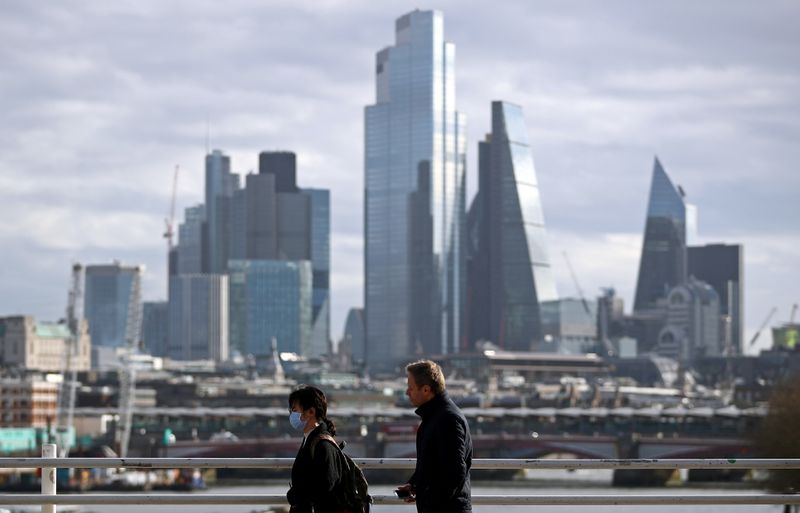 © Reuters. FILE PHOTO: A woman wearing a protective mask walks across Waterloo Bridge in front of the City of London financial district during rush hour, as the number of Coronavirus cases grow around the world, in London