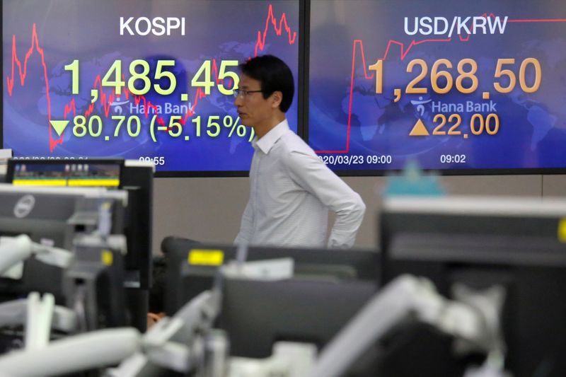 © Reuters. Acionista caminha diante de painel que exibe índices asiáticos e câmbio em Seul