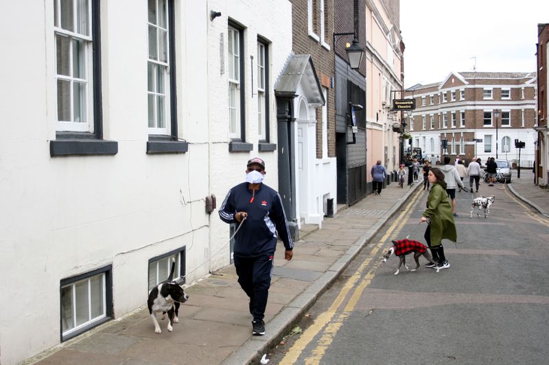&copy; Reuters. Homem com máscara de proteção caminha com seu cachorro em Grenwich