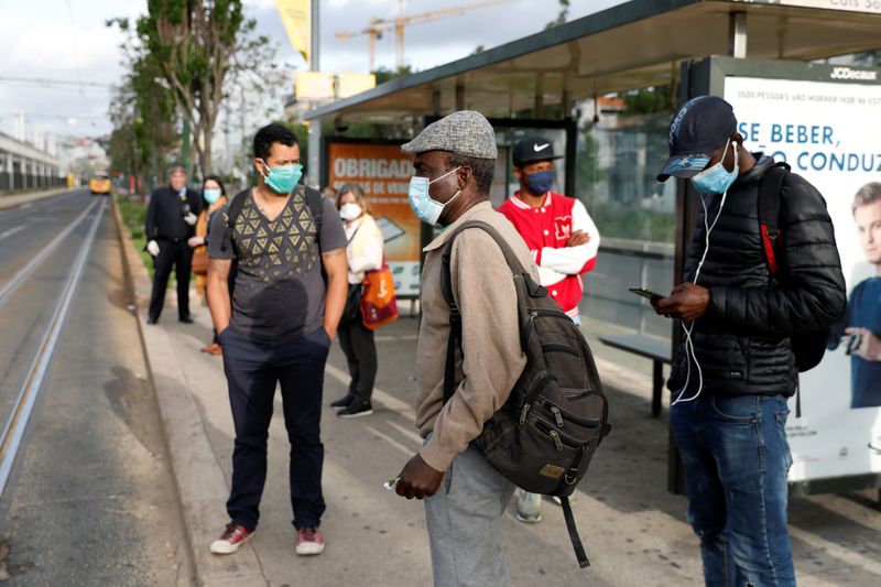 &copy; Reuters. Pessoas com máscaras de proteção em ponto de ônibus em Lisboa