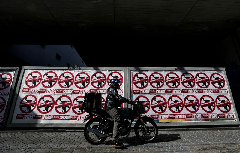 © Reuters. FILE PHOTO: A motorcyclist drives his motorbike past posters on the streets that reads 