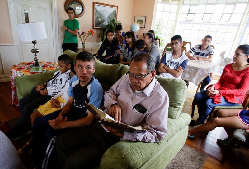 &copy; Reuters. Foto del lunes de Victor Guzman leyendo la Biblia junto a los niños adoptados en su casa en medio de la pandemia de coronavirus en San Jose, Costa Rica