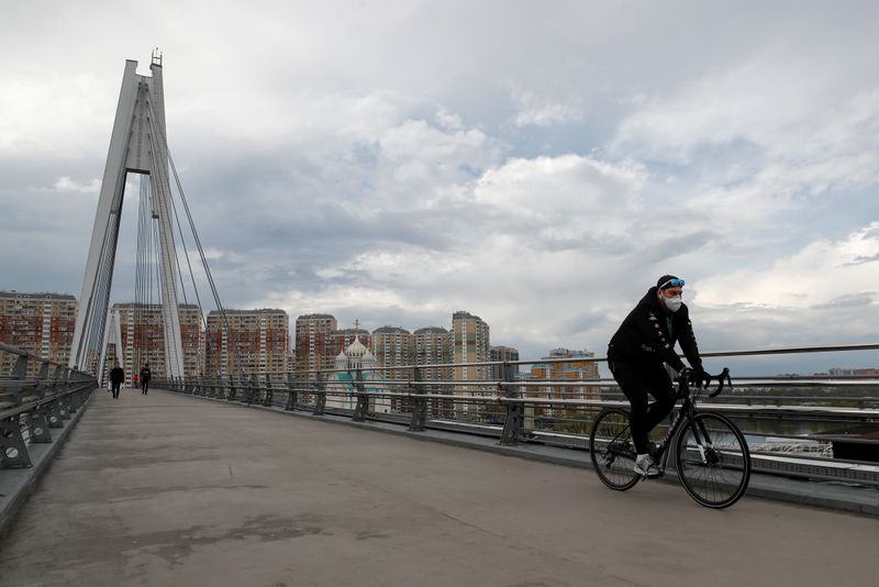 &copy; Reuters. A man wearing a protective face mask rides a bicycle outside Moscow