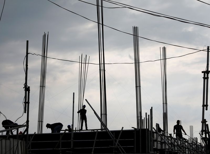 &copy; Reuters. Workers construct beams of a building