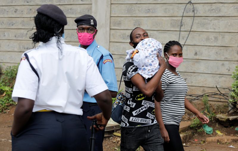 &copy; Reuters. Casal carregando bebê caminha perto de posto de controle policial em Nairóbi