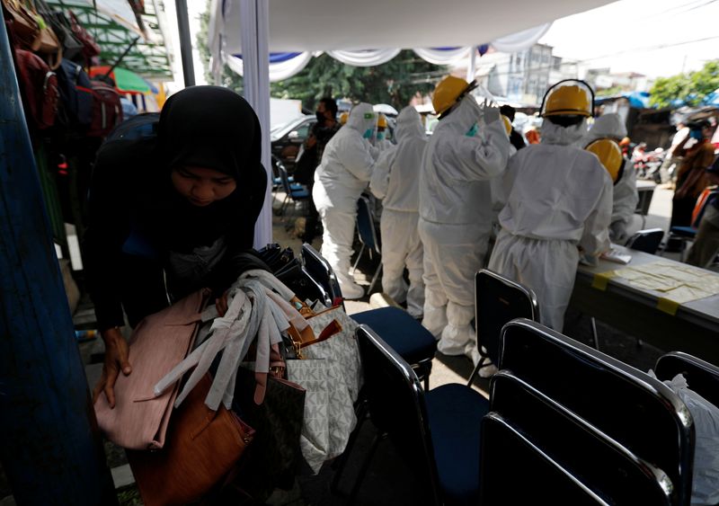 &copy; Reuters. Una vendedora recoge sus productos, mientras los profesionales sanitarios se preparan antes de tomar muestras en un mercado tradicional en Bogor, provincia de Java Occidental, Indonesia