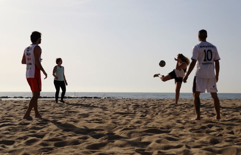 &copy; Reuters. Pessoas jogam futebol em praia de Barcelona