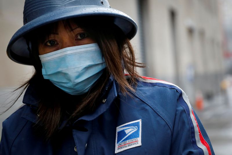 © Reuters. FILE PHOTO: A United States Postal Service (USPS) worker works in the rain in Manhattan during outbreak of coronavirus disease (COVID-19) in New York