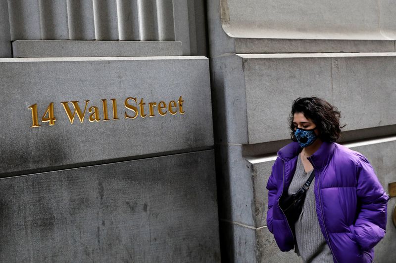 &copy; Reuters. Una donna con indosso la mascherina passeggia lungo Wall Street dopo che ulteriori casi di coronavirus sono stati confermati a New York, New York.