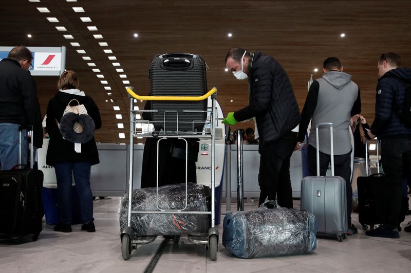 &copy; Reuters. A man wearing a protective face mask and gloves checks in luggage at the Air France desks inside Terminal 2E at Paris Charles de Gaulle airport