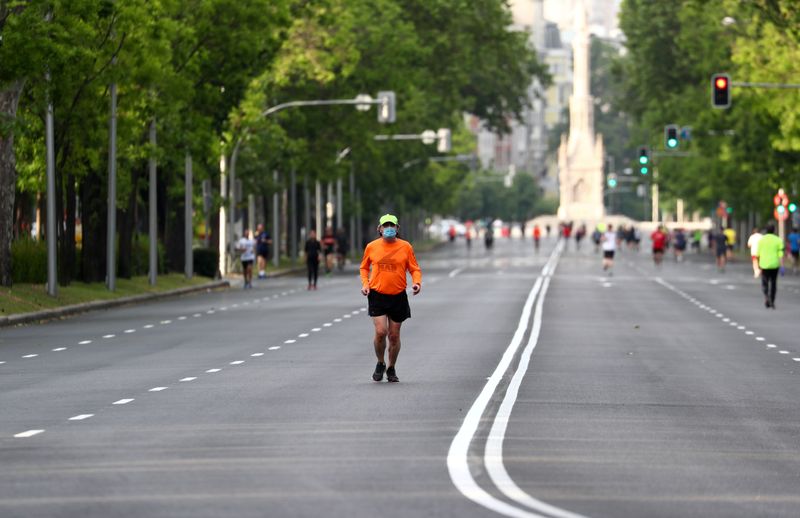 © Reuters. Un hombre con una mascarilla corre por el Paseo de la Castellana en Madrid