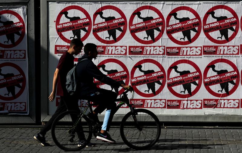 &copy; Reuters. FILE PHOTO: Pedestrians walk past posters on the streets that reads &quot;No to the payment of the debt. Break with the IMF&quot;, in Buenos Aires