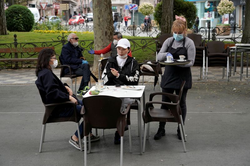 &copy; Reuters. Garçonete com máscara de proteção serve clientes em Cuenca, na Espanha