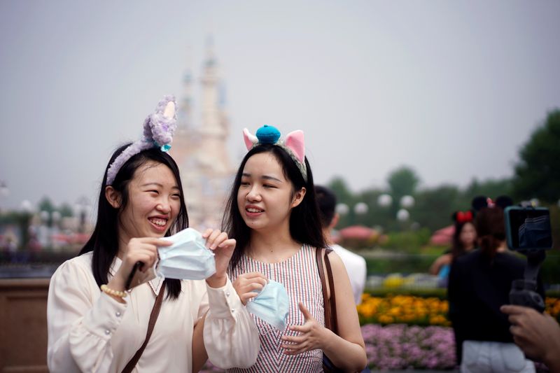 © Reuters. Visitors hold face masks at the Shanghai Disneyland