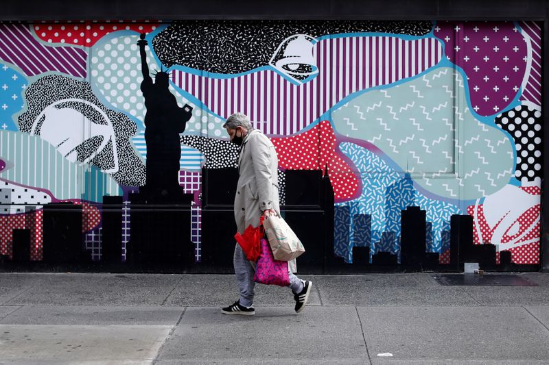 &copy; Reuters. Foto del lunes de un hombre con una máscara pasando delante de una tienda cerrada en Manhattan, en medio de la pandemia de coronavirus