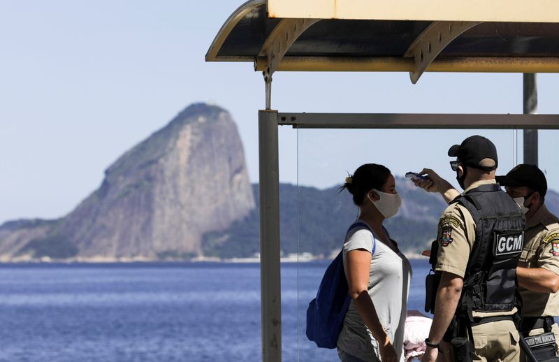 &copy; Reuters. Guardas municipais verificam temperatura de mulher em ponto de ônibus no Rio de Janeiro