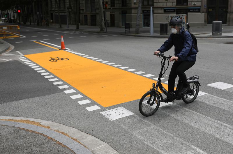 &copy; Reuters. Un hombre con una mascarilla cruza una calle en bicicleta en Barcelona