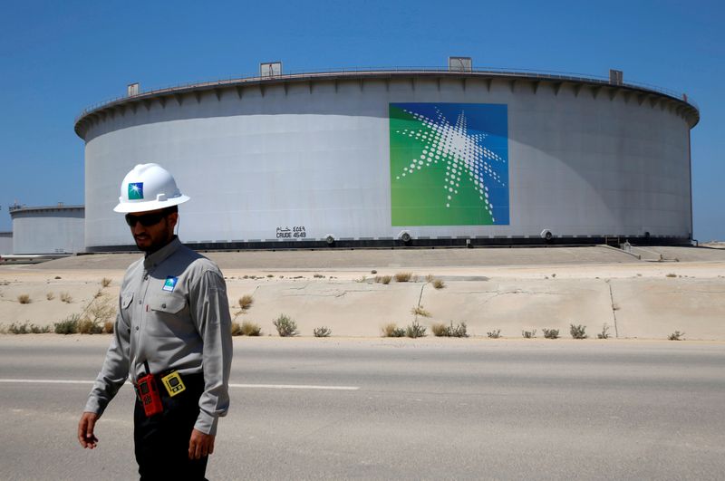 © Reuters. FILE PHOTO: An Aramco employee walks near an oil tank at Saudi Aramco's Ras Tanura oil refinery and oil terminal