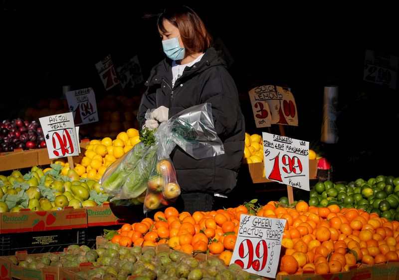 © Reuters. FILE PHOTO: A woman wears a mask and gloves as he shops at a fruit stand, during the outbreak of the coronavirus disease (COVID-19), in Brooklyn, New York