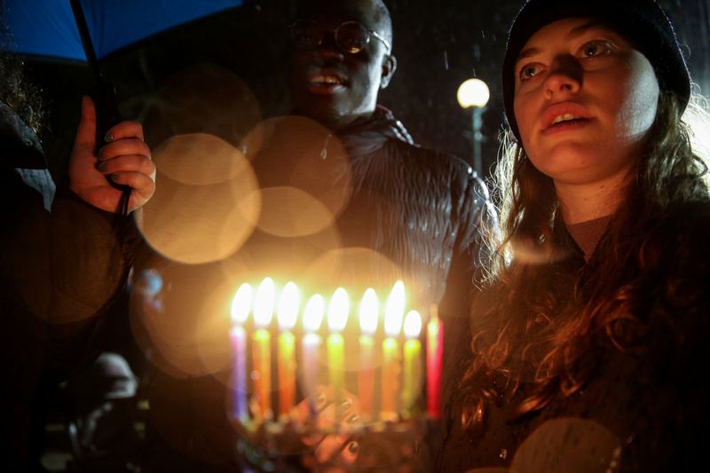 &copy; Reuters. Mulher segura candelabro durante homenagem a vítimas atacadas durante festa na casa de um rabino em Nova York