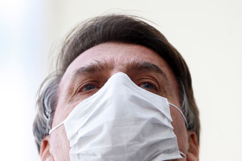 © Reuters. Brazil's President Jair Bolsonaro wearing a protective mask speaks with journalists, amid the coronavirus disease (COVID-19) outbreak, at the Planalto Palace, in Brasilia