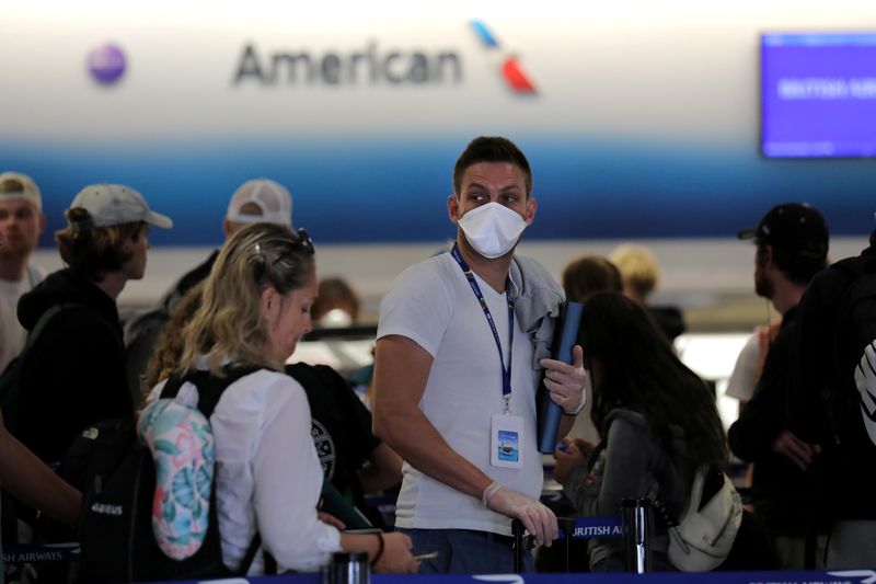 © Reuters. FILE PHOTO: A passenger wearing a mask waits in line to check in for a flight at Miami International Airport