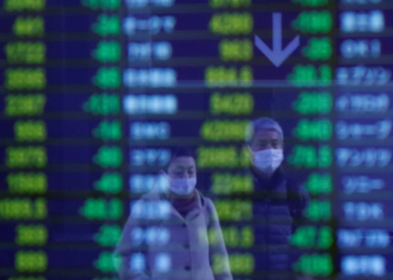 © Reuters. Passersby wearing protective face masks, following an outbreak of the coronavirus, are reflected on a screen displaying stock prices outside a brokerage in Tokyo