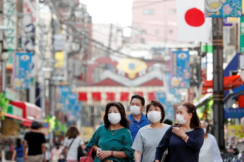 &copy; Reuters. Un grupo de personas con mascarillas pasea por un mercado en Tokio