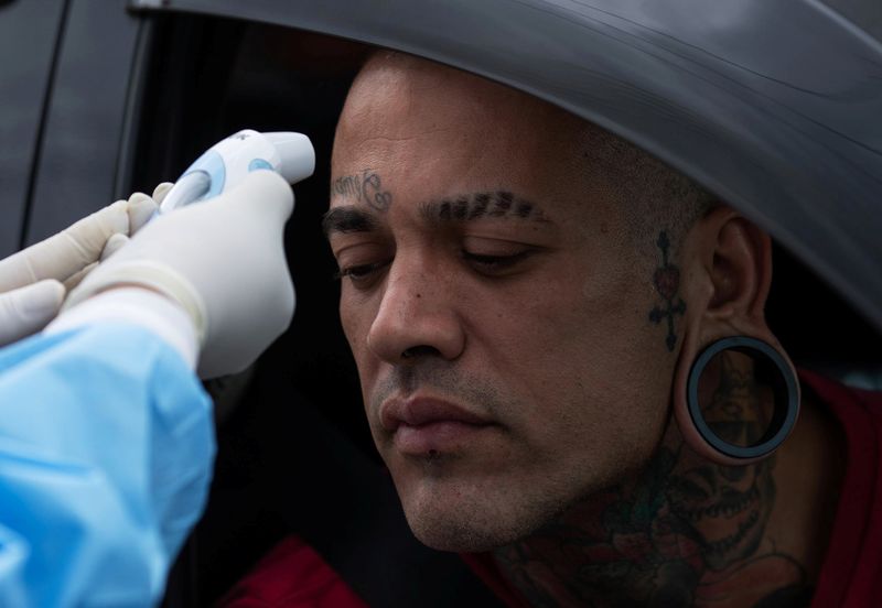 &copy; Reuters. Profissional de saúde monitora temperatura de homem em barreira sanitária em São Sebastião, SP