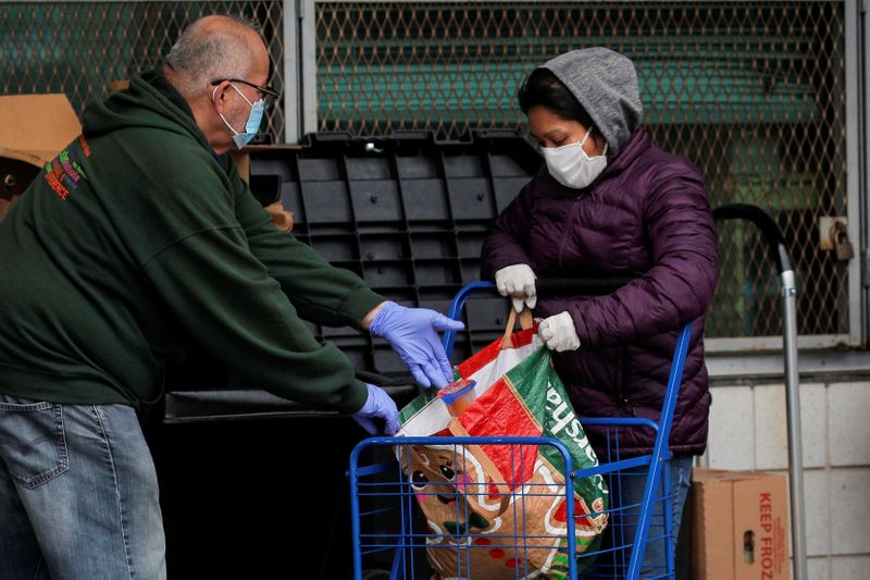 © Reuters. FILE PHOTO: Members of the New York City Department of Probation distribute food to needy residents at a food pantry, during the outbreak of the coronavirus disease (COVID-19) in the Bronx borough of New York