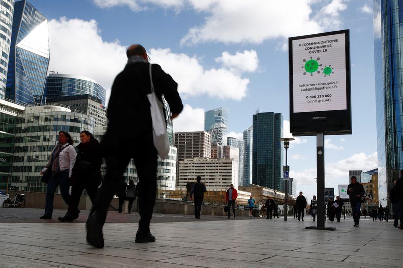 &copy; Reuters. People walk pass a board with information about coronavirus (COVID-19) at the financial and business district of La Defense , as France&apos;s President announced schools, high schools and nurseries will be close as from 16 March until further notice, in 