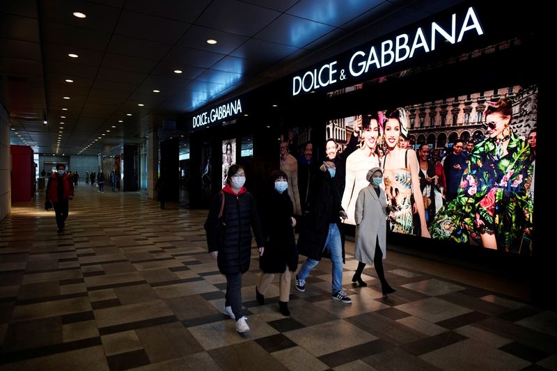 &copy; Reuters. People wearing face masks walk past a Dolce &amp; Gabbana store at a shopping mall in Wuhan