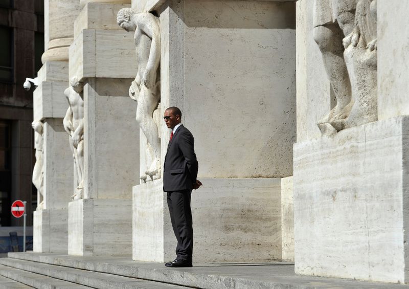 © Reuters. Un uomo in piedi davanti alla sede della Borsa di Milano in centro a Milano