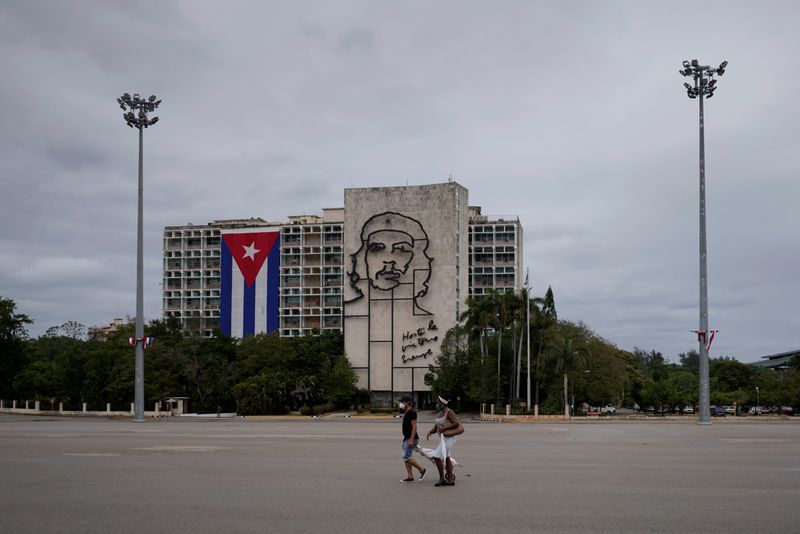 &copy; Reuters. Foto de archivo. Gente camina en la plaza de la Revolución cerca de una imagen del fallecido revolucionario Ernesto &quot;Che&quot; Guevara, en medio de la preocupación por la propagación del brote de la enfermedad coronavirus (COVID-19), en La Habana,