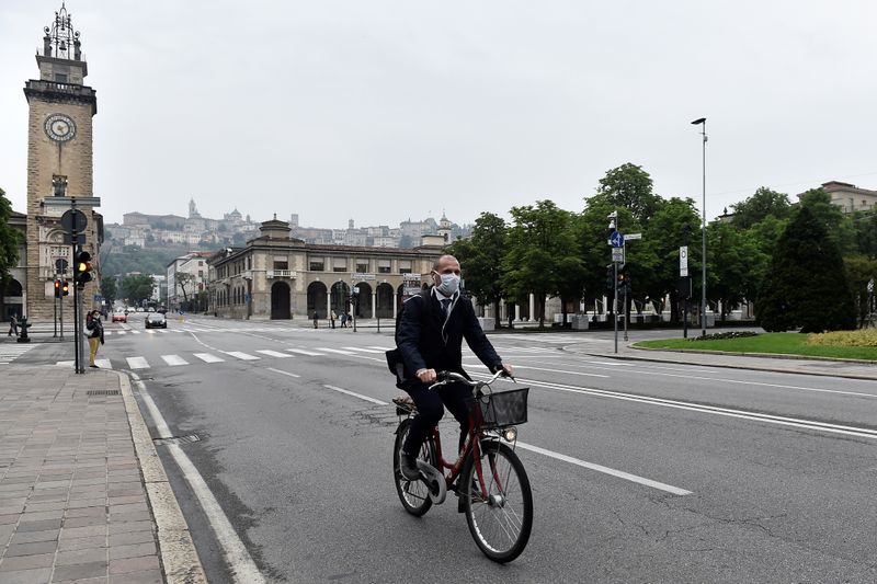 &copy; Reuters. FOTO DE ARCHIVO: Un hombre con mascarilla circula en bicicleta por una calle de Bérgamo