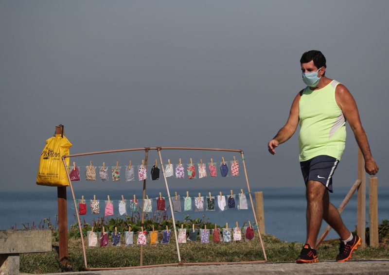 &copy; Reuters. Homem passa por barraca com máscaras à venda na praia da Barra da Tijuca, no Rio de Janeiro