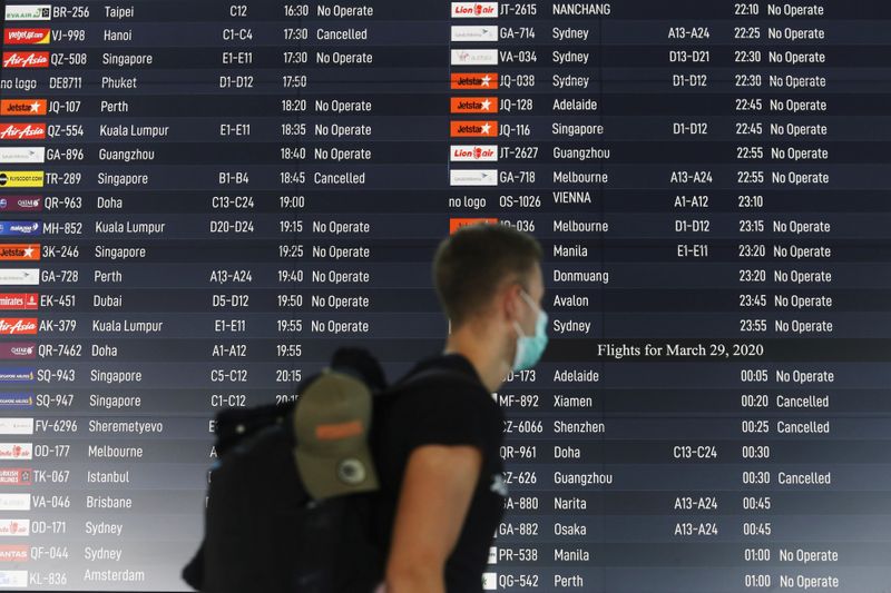 © Reuters. Turista passa por painel com informações de voos cancelados em aeroporto de Bali