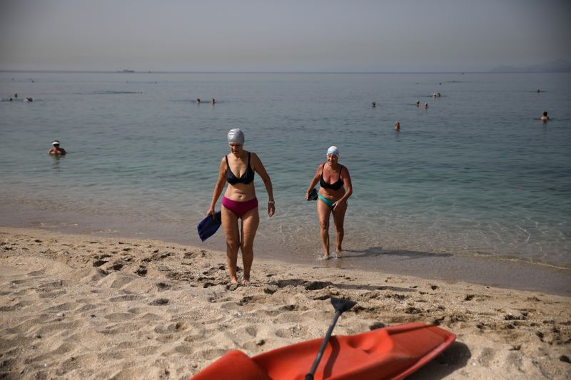 &copy; Reuters. اليونانيون يعودون للشواطئ وسط موجة حارة مع مسافات بين المظلات