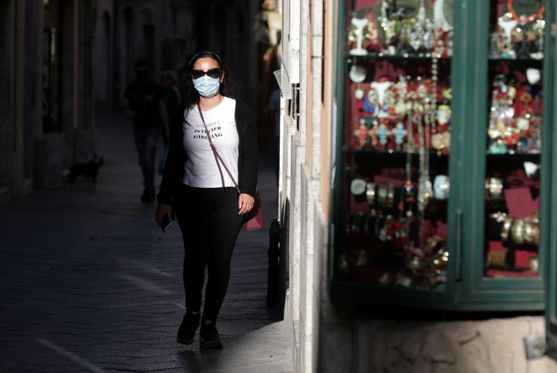 &copy; Reuters. FOTO DE ARCHIVO: Una mujer con mascarilla camina por una calle en Taormina, Italia