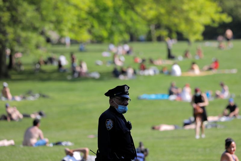 &copy; Reuters. FOTO DE ARCHIVO: Un oficial del Departamento de Policía de la Ciudad de Nueva York (NYPD) con mascarilla observa cómo las personas se reúnen en el Sheep Meadow en Central Park durante el brote de COVID-19 en Manhattan, Nueva York. 15 de mayo de 2020.