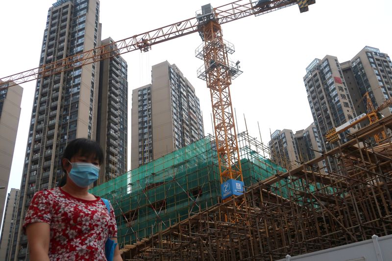 &copy; Reuters. Woman wearing a face mask walks past a construction site near residential buildings in Shenzhen, following the novel coronavirus disease (COVID-19) outbreak