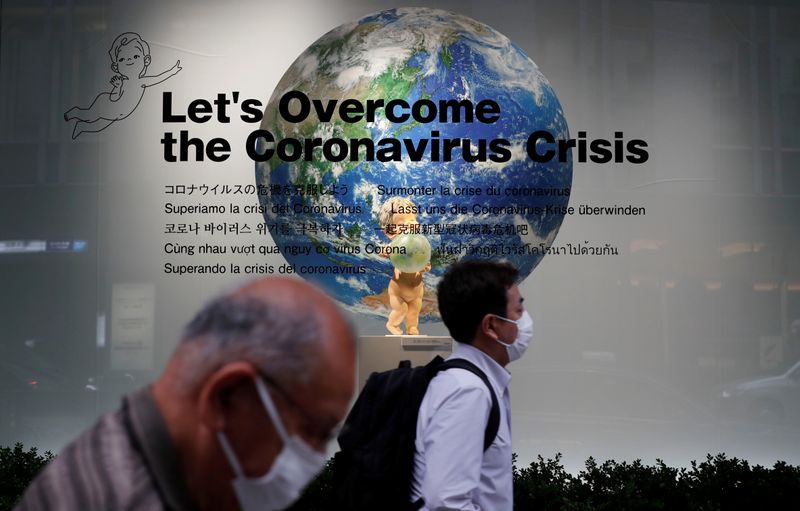 &copy; Reuters. Прохожие в масках на фоне витрины универмага в Токио во время пандемии COVID-19