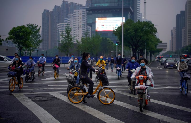 &copy; Reuters. FOTO DE ARCHIVO: Personas con mascarillas circulan en bicicleta en Wuhan
