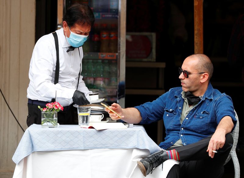 &copy; Reuters. Homem é servido por garçom com máscara de proteção em restaurante de Roma