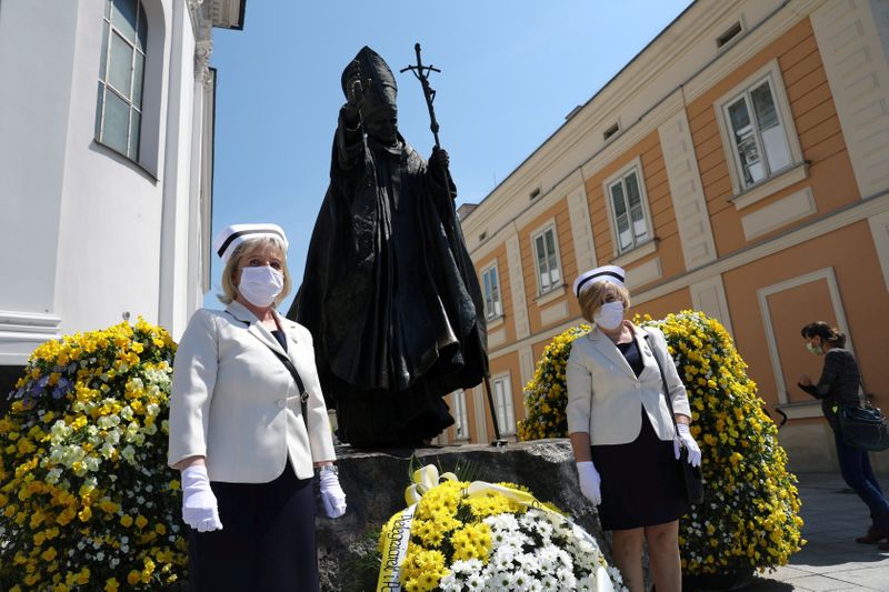 &copy; Reuters. Nurses in protective masks attend a ceremony to commemorate the 100th anniversary of the birth of late Pope John Paul II next to his monument in Wadowice