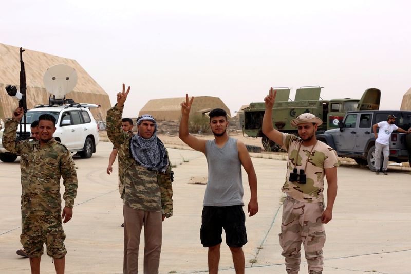 &copy; Reuters. FILE PHOTO: Members of Libya&apos;s internationally recognised government flash victory signs after taking control of Watiya air base