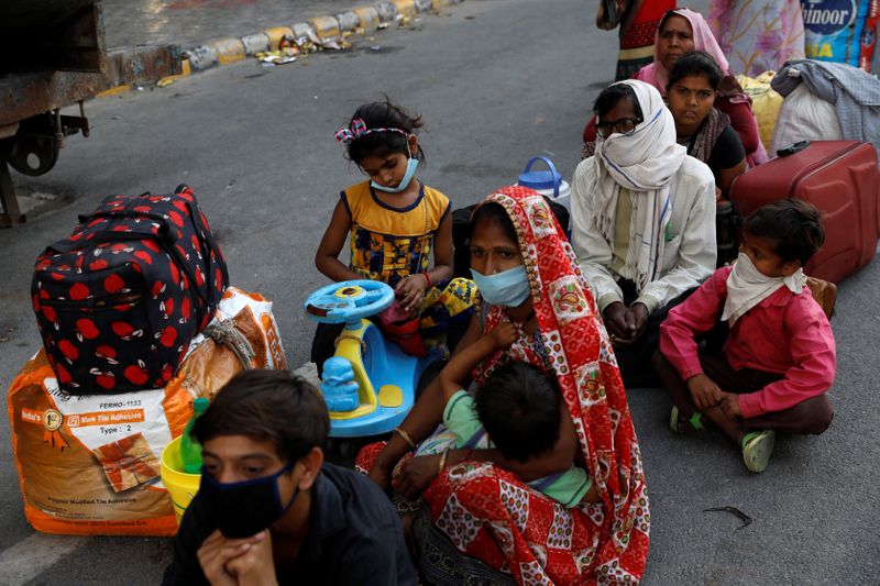 &copy; Reuters. Família aguarda em Noida, na Índia, para embarcar em ônibus de volta para casa